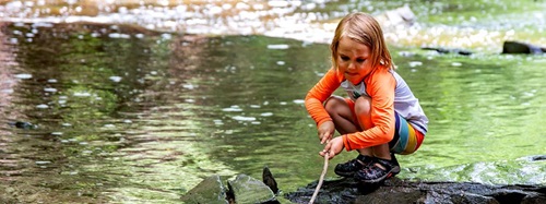 girl playing by a stream