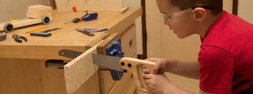 boy sawing a piece of wood